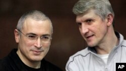 Mikhail Khodorkovsky, left, and his co-defendant Platon Lebedev talk behind a glass enclosure at a court room in Moscow, Russia, Dec. 30, 2010. 