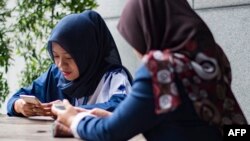 Dua remaja putri menggunakan ponselnya untuk mengakses internet di sebuah cafe di Jakarta (foto: ilustrasi). 