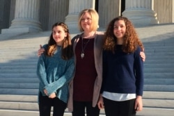 FILE - Kendra Espinoza of Kalispell, Montana stands with her daughters Naomi and Sarah outside the U.S. Supreme Court, January 22, 2020, in Washington. Espinoza is the lead plaintiff in the case