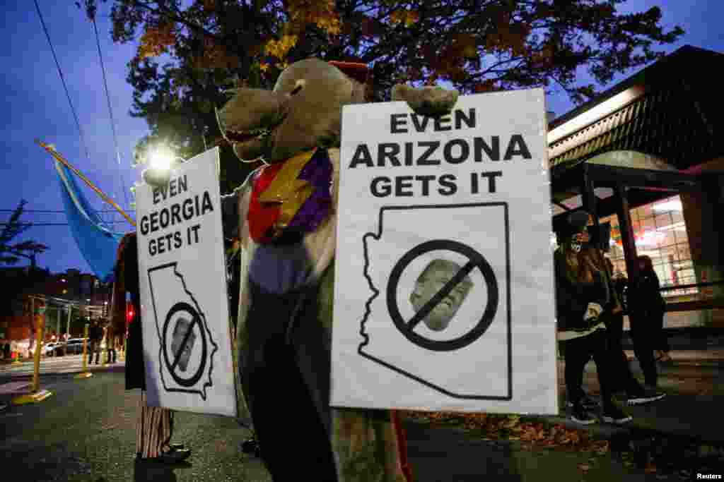 A person wearing a costume holds placards after news media announced that Democratic 2020 U.S. presidential nominee Joe Biden has won the 2020 U.S. presidential election, in Seattle, Washington.