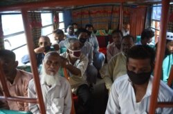 People sit in a mini bus after the government resumed public transport services, in Pakistan's port city of Karachi, June 3, 2020.