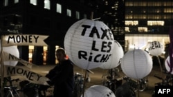 An attendee with a "Tax the rich" lantern as demonstrators prepare an illuminated "Tax'N Roll" parade from La Defense to Place Vauban, Courbevoie, France, on November 3, 2023 The protest was part of a "Power Up" action of 350.org ahead of COP28 conference starting November 24.