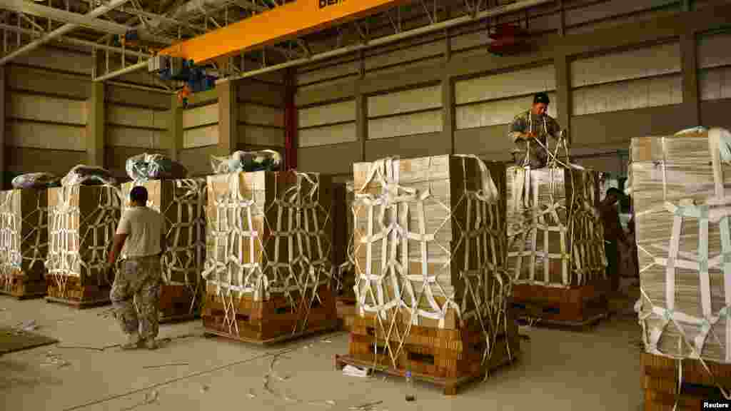 U.S. Army parachute riggers with the 11th Quartermaster Company, 264th Combat Sustainment Support Battalion, 82nd Sustainment Brigade, palletize halal meals for a humanitarian airdrop over Iraq at an undisclosed location in Southwest Asia in this Aug. 7 p