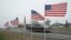 Eleven flags, one for each service member aboard, line the road across from the staging area where crews search waters around the Navarre Bridge following the crash of a military helicopter, east of Pensacola, Florida, March 11, 2015. 
