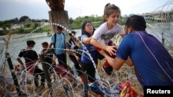 Migrants from Venezuela make their way through the razor wire after crossing the Rio Grande into the United States in Eagle Pass, Texas, Sept. 26, 2023.