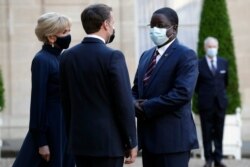 French President Emmanuel Macron, center, and his wife Brigitte Macron, left, welcome Chadian Prime Minister Albert Pahimi Padacke, right, for a dinner with leaders of African states, at the Elysee Palace, in Paris, May 17, 2021.