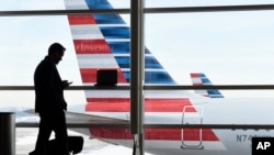 FILE - A passenger talks on the phone as American Airlines jets sit parked at their gates at Washington's Ronald Reagan National Airport, Jan. 25, 2016. A civil rights group is suing the Trump administration for details on how data found by immigration officials on travelers' electronic devices is kept or shared.