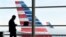 FILE - A passenger talks on the phone as American Airlines jets sit parked at their gates at Washington's Ronald Reagan National Airport, Jan. 25, 2016. 