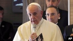 FILE - Pope Francis holds a photo by U.S. photographer Joseph Roger O'Donnell of child victims of Nagasaki bombing, aboard his flight to Santiago, Chile, Jan. 15, 2018. The Vatican said Friday the pontiff will visit Thailand and Japan, Nov. 19-26.