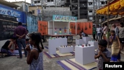 Residents gather around a mobile museum displayed on an improvised handcart in Dharavi, one of Asia's largest slums, in Mumbai, India, Feb. 18, 2016. 