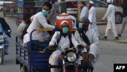 FILE - Pakistani Muslims wearing facemasks as a preventive measure against the COVID-19, arrive for the annual Tablighi Ijtema religious gathering in Raiwind on the outskirts of Lahore on Nov. 5, 2020.