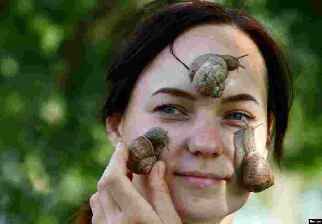 Victoria Rabkova, wife of the farmer Vladimir Rabkov, holds snails on her face at their farm in the village of Dolginovo, Belarus.