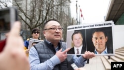 Louis Huang of Vancouver Freedom and Democracy for China holding photos of Canadians Michael Spavor and Michael Kovrig, who have been detained in China since 2018.