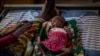 FILE - In this May 11, 2021, photo, Abeba Gebru, 37, from the village of Getskimilesley, sits with her malnourished daughter, Tigsti Mahderekal, 20 days old, in the treatment tent of a medical clinic in Abi Adi, Tigray region, Ethiopia. 