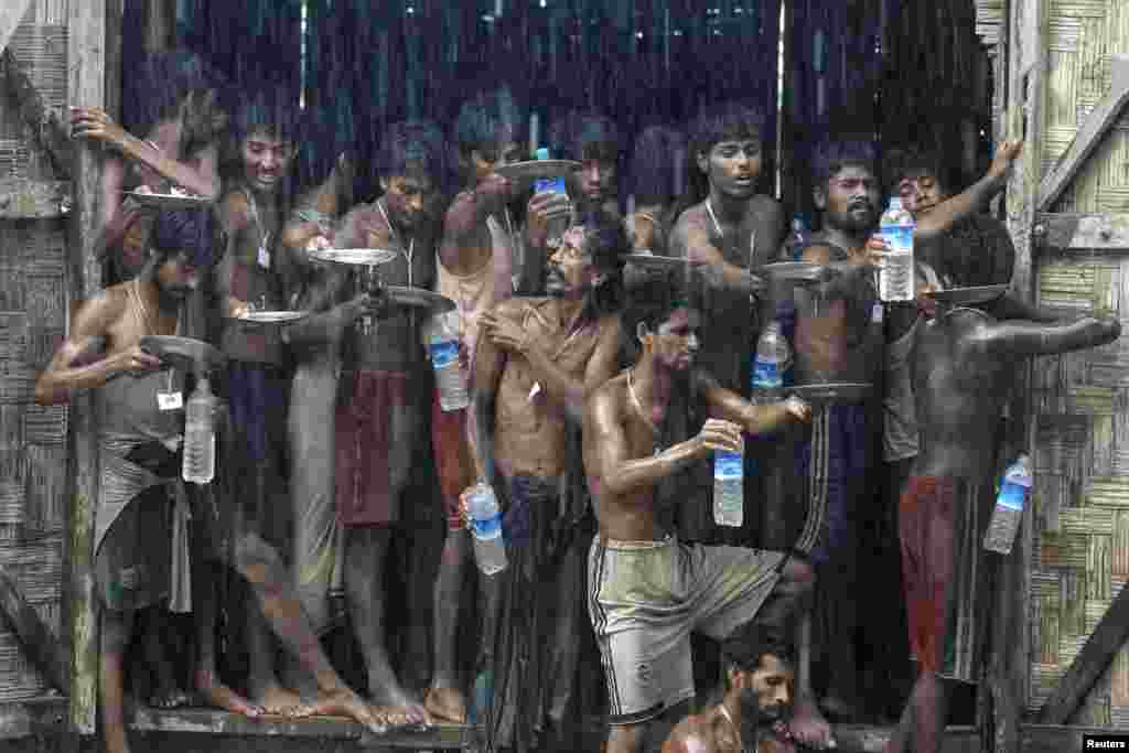 Migrants, who were found at sea on a boat, collect rainwater during a heavy rain fall at a temporary refuge camp near Kanyin Chaung jetty, outside Maungdaw township, northern Rakhine state, Myanmar.