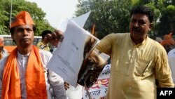 FILE - Demonstrators burn a copy of the report of the Office of the United Nations High Commissioner for Human Rights during a protest outside the United Nations office in New Delhi, June 25, 2018. The first-ever U.N. report on Kashmir accuses India and Pakistan governments of committing atrocities in the divided region.