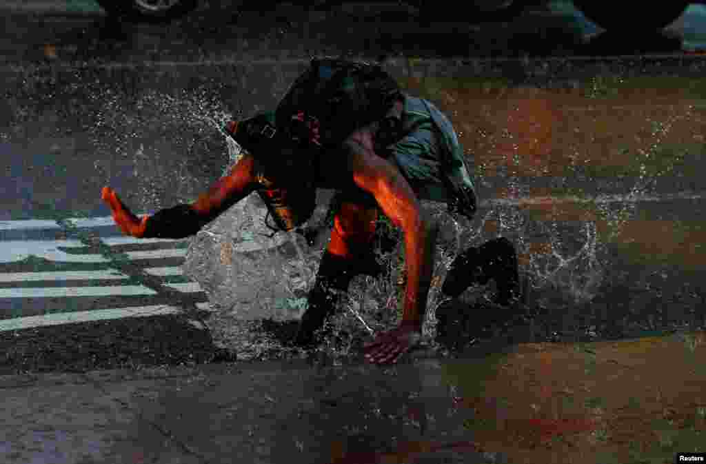 A man splashes in a puddle in Times Square during a heavy midday downpour in New York City, July 17, 2018.