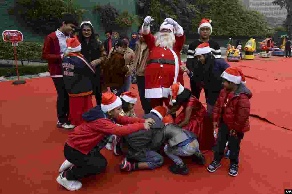 بنگلہ دیش کے شہر ڈھاکہ میں سانتا کلاز کے روپ میں موجود ایک شخص بچوں میں چاکلیٹس تقسیم کر رہا ہے۔&nbsp;