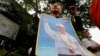 A supporter of the former opposition Cambodia National Rescue Party holds a poster of party leader Kem Sokha as she stands during a protest rally at a blocked street near the Appeals Court where party leader Kem Sokha is to appear, in Phnom Penh, Cambodia, Tuesday, March 27, 2018. The court on Tuesday is planning to hear a bail request for Kem Sokha who has been charged with treason. (AP Photo/Heng Sinith)