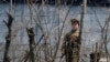 FILE - A North Korean prison policewoman stands guard behind fences at a jail on the banks of Yalu River near the Chongsong county of North Korea, opposite the Chinese border city of Dandong.