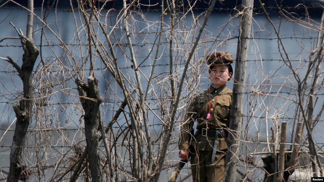 Seorang polisi wanita Korea Utara berjaga di balik pagar sebuah penjara di tepi Sungai Yalu dekat daerah Chongsong Korea Utara, seberang kota perbatasan China Dandong. (Foto: dok).
