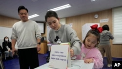 韩国首尔一对母女在一处投票站为国会议员选举投票。（2024年4月10日）
