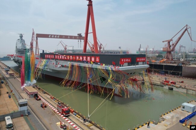 In this photo released by Xinhua News Agency, colored smoke marks the launch ceremony for China's third aircraft carrier named Fujian in Shanghai on Friday, June 17, 2022. (Li Gang/Xinhua via AP)