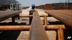 FILE - Jose Mata grinds a steel pipe at the Borusan Mannesmann plant in Baytown, Texas, April 23, 2018. President Donald Trump extended tariff exemptions on aluminum and steel exports from the European Union, Canada and Mexico late on April 30, 2018, just hours before they were to run out.