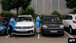 FILE - Medical technicians administer COVID-19 swab tests at a drive-through testing site at Wits University, Braamfontein, Johannesburg, South Africa, Jan. 5, 2021.