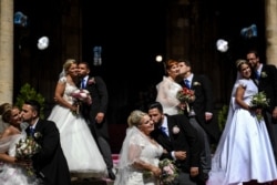 Brides and grooms kiss as they pose for a photo outside Lisbon's Cathedral following their wedding ceremonies, in Lisbon, Portugal, June 12, 2019.