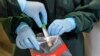 Two nurses demonstrate taking a sample for a coronavirus test at the infection station of the university hospital in Essen, Germany, March 12, 2020. 