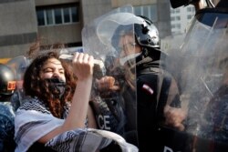 FILE - An anti-government protester uses a stone to beat on the shield of a riot policeman, during a protest against the deepening financial crisis, in Beirut, Lebanon, April 28, 2020.