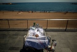 FILE - Francisco Espana, 60, faces the Mediterranean from a promenade next to a hospital in Barcelona, Spain, Sept. 4, 2020. He spent 52 days in intensive care at the hospital, but was allowed by his doctors to spend 10 minutes outdoors for recovery.