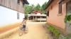 FILE - A boy rides his bicycle through Houaygno village, northern Laos, Nov. 4, 2019. 