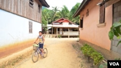 FILE - A boy rides his bicycle through Houaygno village, northern Laos, Nov. 4, 2019. 