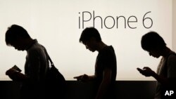 File - People wait to buy the Apple iPhone 6 and 6 Plus devices outside an Apple store in Hong Kong, Sept. 19, 2014.