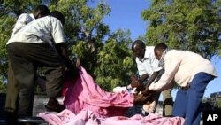 A body is loaded onto the flatbed of a truck by relatives at Medina hospital, in Mogadishu, Somalia, Jan. 31, 2011.