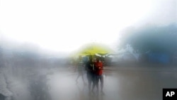 People walk in the rain in Port-au-Prince on 05 Nov 2010