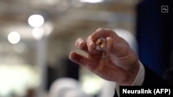 FILE - This video grab made from the online Neuralink livestream shows the Neuralink disk implant held by Elon Musk during the presentation, Aug. 28, 2020. Musk said recently that a third person has received an implant from his brain-computer interface company.