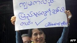 Аун Сан Су Чжи показывает плакат «Я люблю людей»
