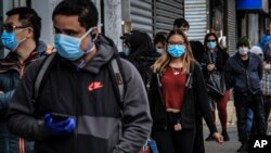 FILE - People in Brooklyn's Sunset Park, a neighborhood with one of the New York's largest Mexican and Hispanic community, wear masks to protect against the coronavirus while waiting in line to enter a store, May 5, 2020, in New York. 