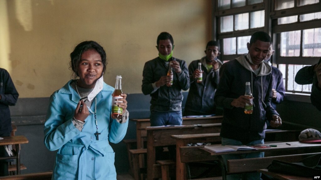 Students drink from bottles of Covid Organics, a herbal tea touted by Madagascar President Andry Rajoelina as a powerful remedy against COVID-19, at a high school in Antananarivo, April 23, 2020.