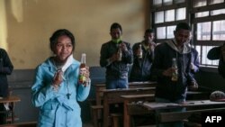 Des élèves malgaches boivent des bouteilles de Covid Organics, une tisane, présentée par le président malgache Andry Rajoelina comme un puissant remède contre le coronavirus COVID-19.