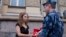 Maria Alekhina, a Russian activist of the feminist protest group Pussy Riot, talks to a policeman as she holds a protest against torture in front of the Federal Penitentiary in Moscow, Russia, Aug. 7, 2018. 