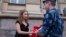 Russian activist of the feminist protest group Pussy Riot Maria Alekhina talks to a policeman as she holds a protest in front of the Federal Penitentiary building in Moscow, Russia, Aug. 7, 2018. 