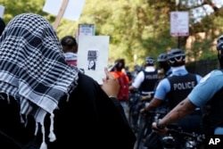 FILE - A pro-Palestinian demonstrator outside the Democratic National Convention in Chicago on Aug. 19, 2024, holds a small poster that includes an image of Democratic presidential nominee Kamala Harris with the words "Genocide is Fascism."