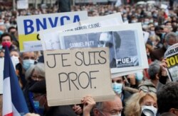 People gather at the Place de la Republique in Paris, to pay tribute to Samuel Paty, Oct. 18, 2020. Placard reads 'I am a teacher'.