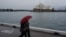 People share an umbrella while walking along the waterfront near the Sydney Opera House as eastern Australia experiences a winter cold front, in Sydney, Australia, June 10, 2021.