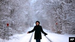 Ellen Werner enjoys the snow-covered landscape following an early spring snowstorm that dumped several inches of heavy, wet snow, in Freeport, Maine.