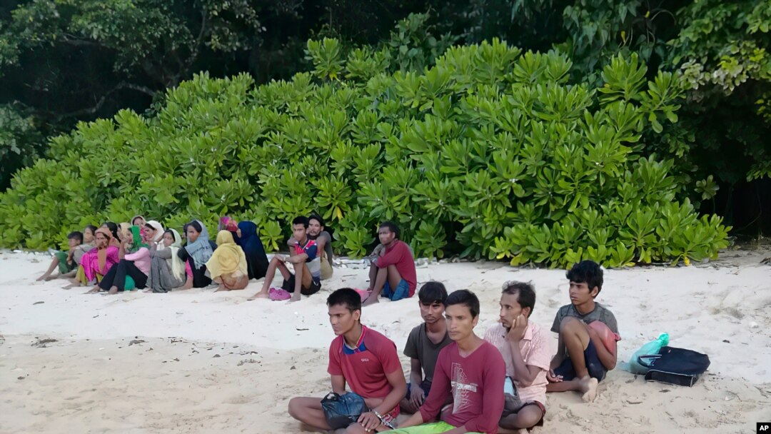 A photo taken July 26, 2020, by the Malaysian Maritime Enforcement Agency, shows Rohingya refugees, who were thought to have drowned, sitting on a beach on Rebak Island, off the resort island of Langkawi, Malaysia.
